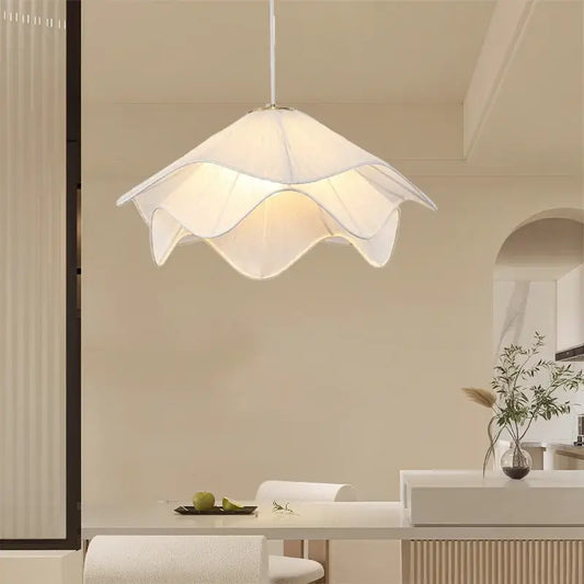 A modern white fabric pendant light with a delicate petal design hangs from the ceiling providing a warm glow