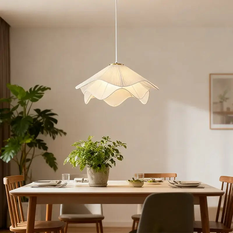 Modern off-white fabric pendant light with petal design and warm glow hanging above dining table cord pendant