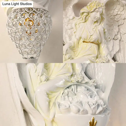Modern white resin angel wall light with gold accents and detailed wings holding a basket of roses for bedroom angel wall use