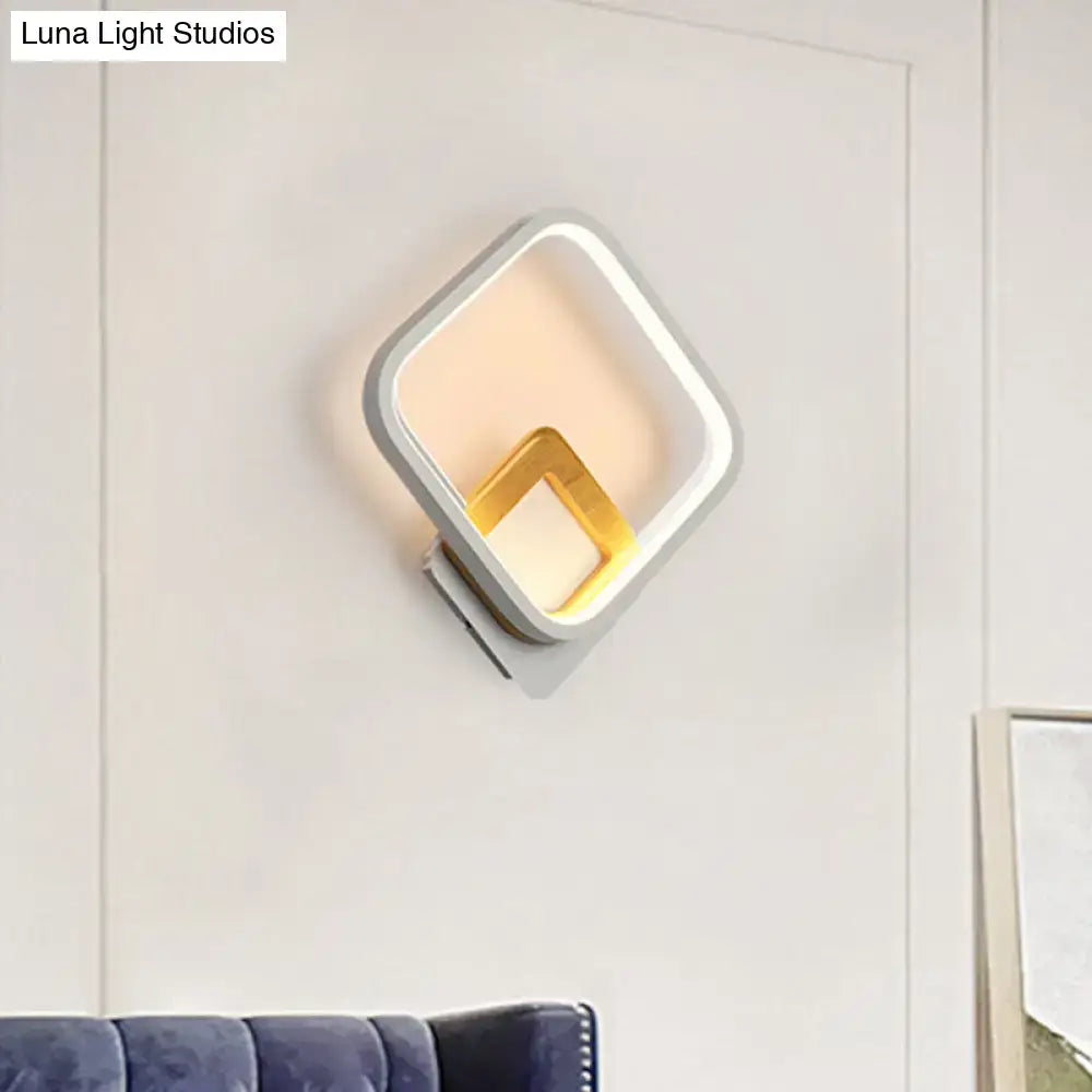 Modern white rhombus wall sconce with sleek white and gold frame emitting warm ambient light for bedroom use