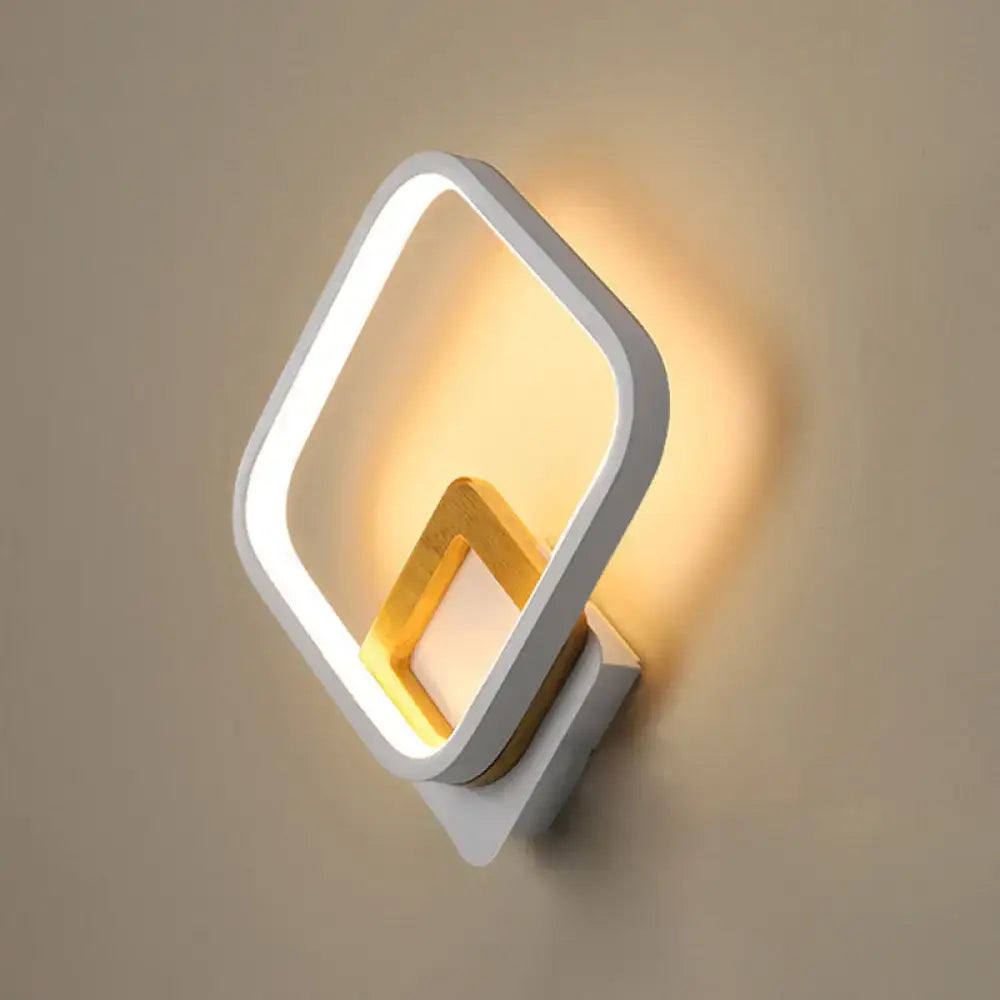 Modern white rhombus wall sconce with gold geometric edges and wood detail illuminated for bedroom lighting