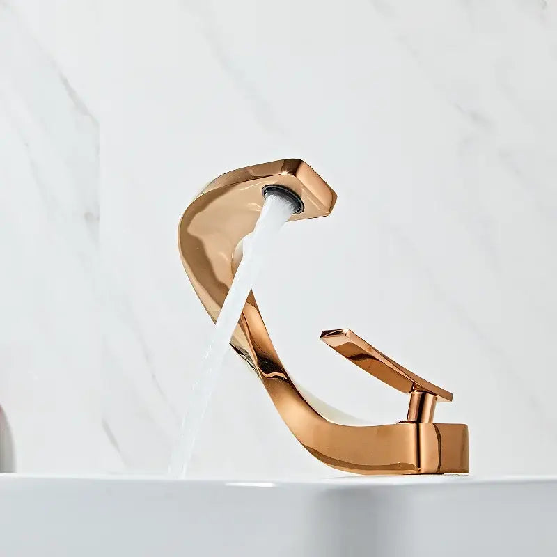 A modern white and rose gold basin faucet with an elegant rose gold finish and curved waterfall tap design