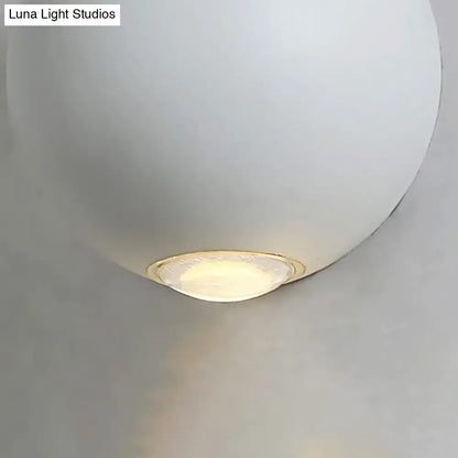 A sleek matte white spherical wall light fixture with warm-toned led light for modern outdoor use