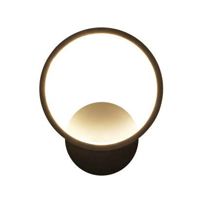 Modern black white bedside wall lamp with circular metal frame and warm glowing translucent diffuser for minimalist bedroom lighting