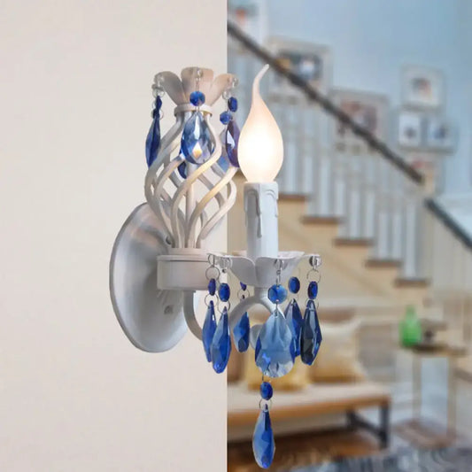 Modern white wall light with blue crystal draping featuring exposed bulb and dangling crystal droplets bedroom sconce