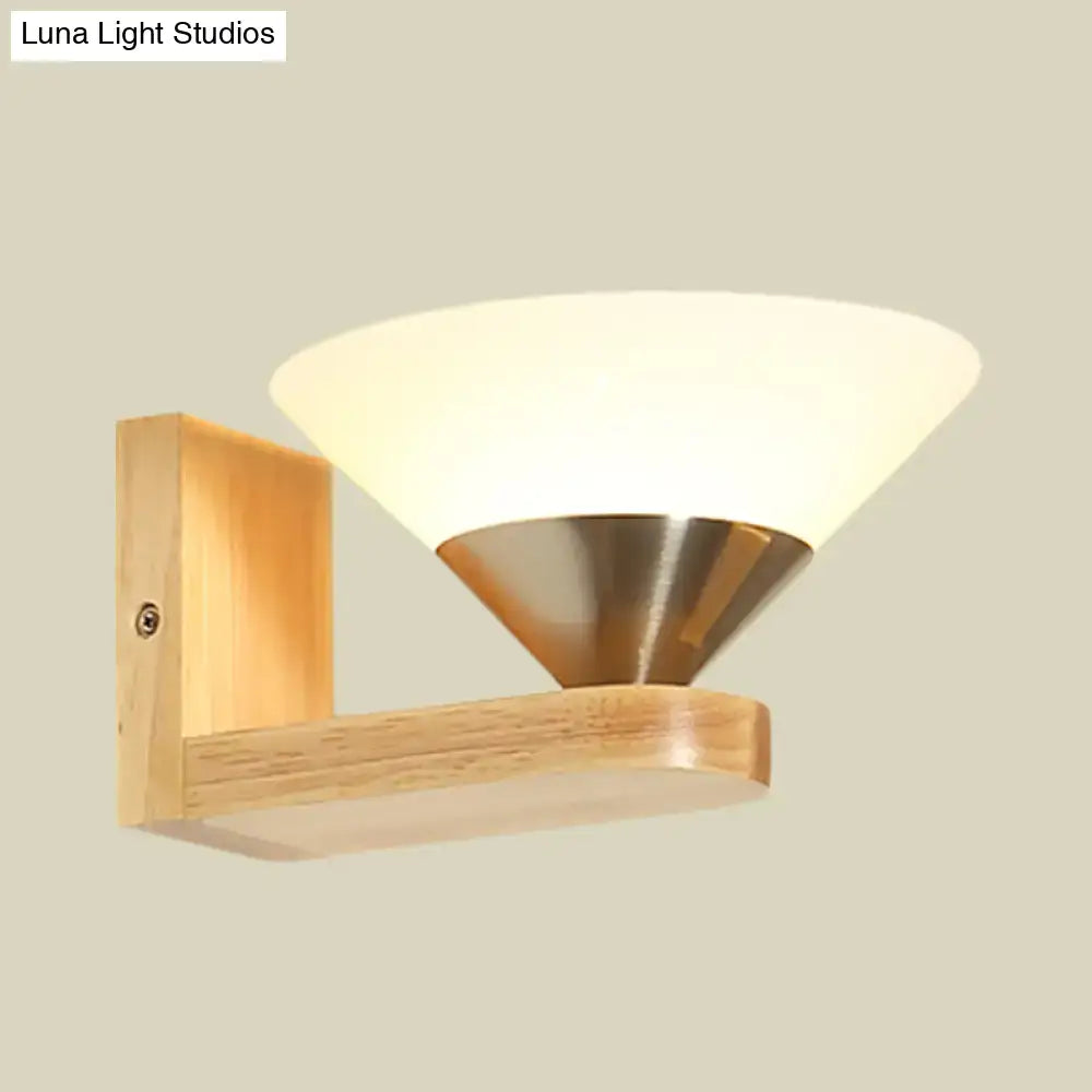 Modern wood and brass wall lamp with warm frosted glass shade and brushed brass cone base on light wood background