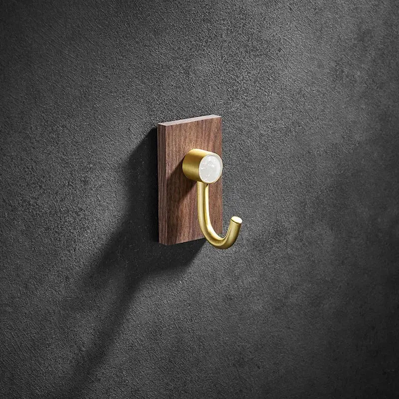 A sleek brass brushed gold wall hook mounted on a dark wood plaque for modern kitchen decorbites brass brushed design