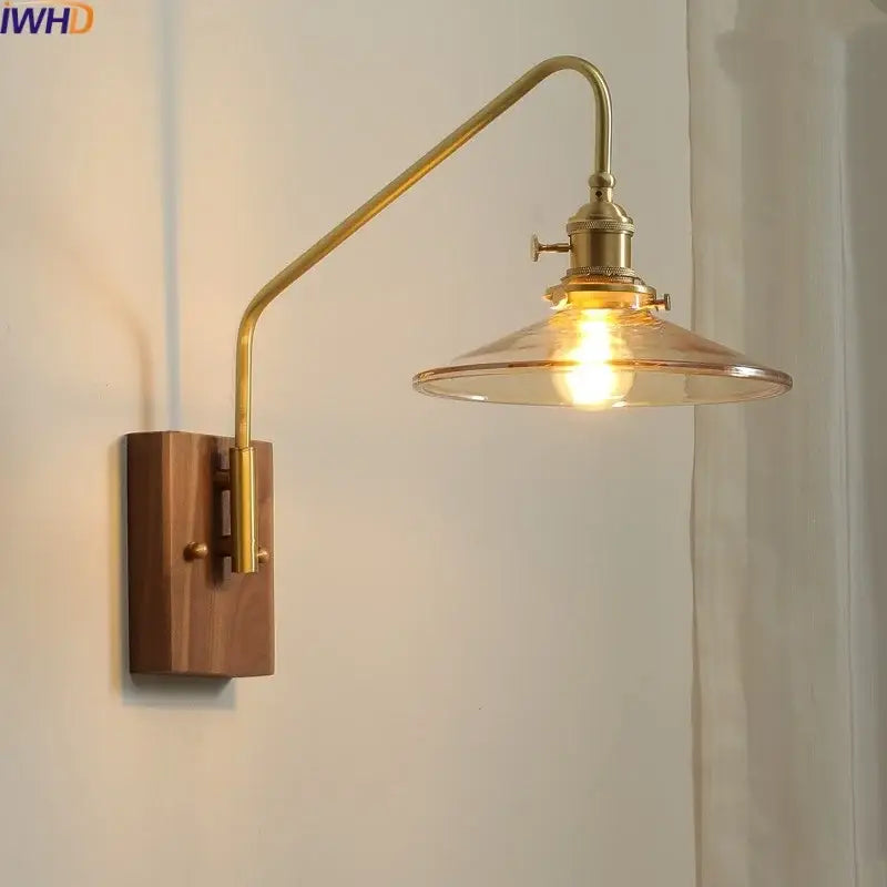 Modern brass-arm wall sconce with wooden base and clear glass copper led shade for bedroom or stair lighting