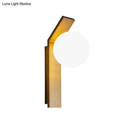 Modern gold-toned dining room wall sconce with sleek metal frame and round frosted milk glass shade