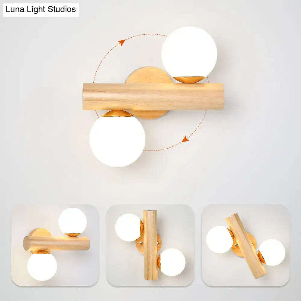 Modern wood and white glass ball rotating wall sconce with light wood finish and adjustable brass fixtures for bedroom light