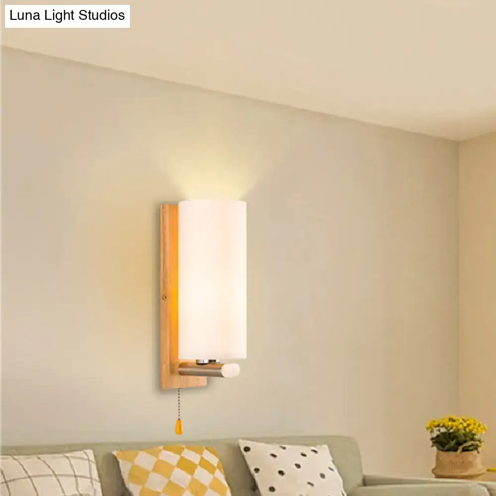 Modern wood and white glass wall sconce with warm wooden frame and brass pull chain light for bedroom use