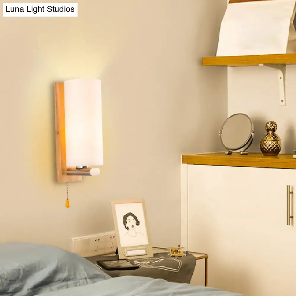 Modern wood and white glass wall sconce with warm-toned wooden frame frosted shade and pull chain light type for bedroom