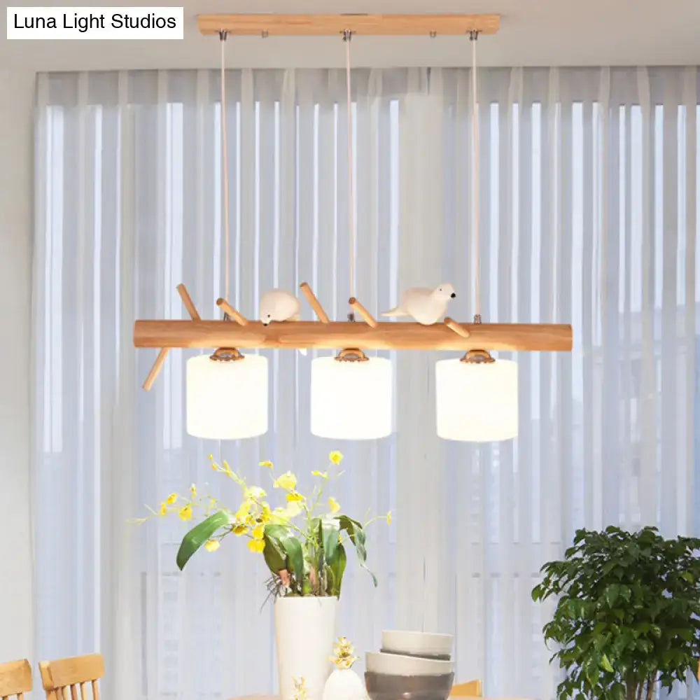 Modern wood cylinder hanging light with white glass shades and bird figurines on natural wood branch design for kitchen