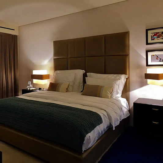 Brown tufted leather headboard with square panels beside modern wood deco milk glass wall lamp bedroom sconce