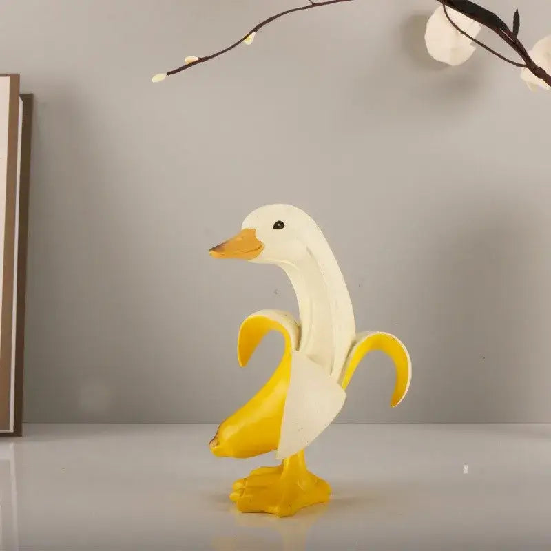 White duck figurine with yellow beak feet and banana peel design inspired by modern banana balloon dog sculpture decor