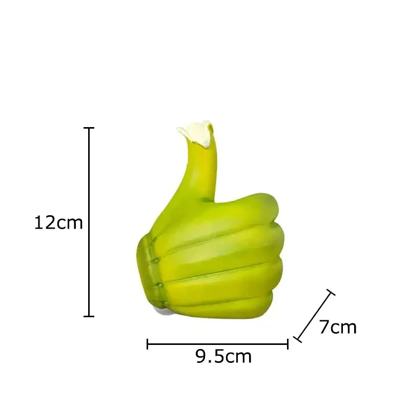 A lime green glossy plastic thumbs-up air freshener with white cap beside a modern yellow banana fist resin statue desk ornament