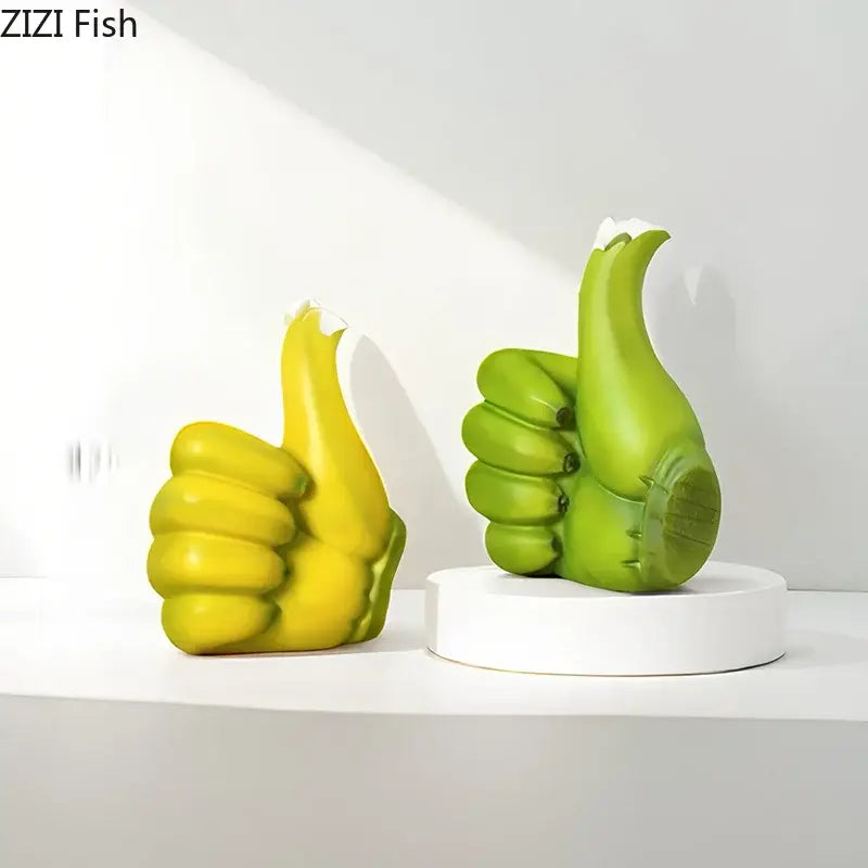 Vibrant yellow and green resin banana fist desk ornament with a thumbs-up design on a white pedestal for bedroom decor