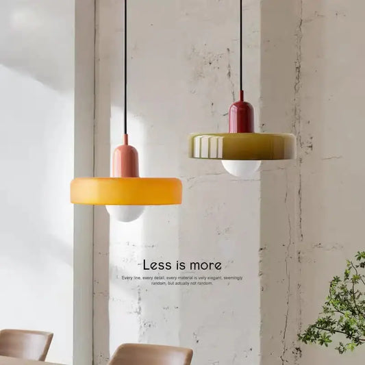 Two modern glass chandelier pendant lights with matte yellow and olive green circular shades for bedroom use