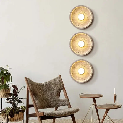 Three circular modern yellow stone led wall lamps with textured concrete finish and warm glowing centers for bedroom use