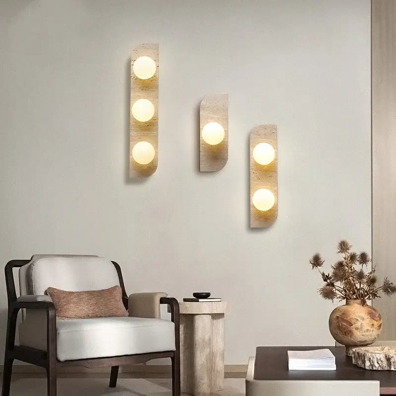 Three modern yellow travertine led wall lamps with warm glowing bulbs set in textured stone panels for bedroom lighting