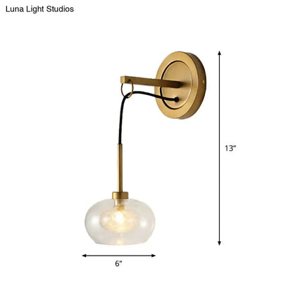 Brass-finished modernist wall sconce with amber white glass globe and black cord for bedroom lighting