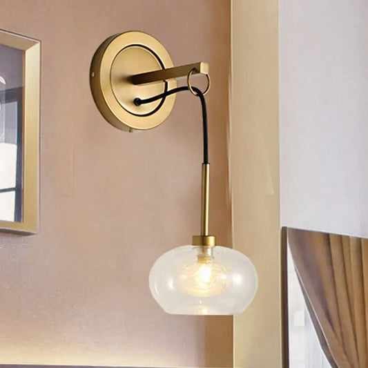 Modernist gold-toned wall sconce with amber white glass globe shade and black cord for bedroom lighting satisfaction guarantee