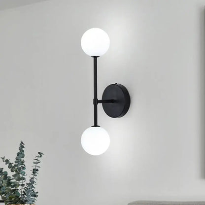Modernist black wall sconce with gold finish and two frosted glass globe shades for living room lighting
