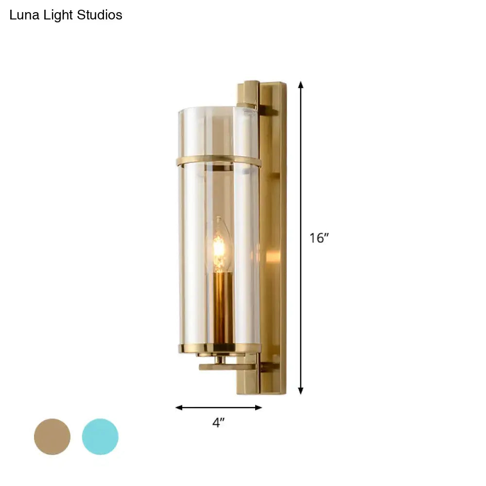 Modernist brass wall lamp with a clear cylindrical glass shade and exposed filament bulb for bedroom sconce light use