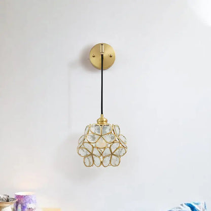 A delicate gold-toned modernist brass floral glass bulb bedside sconce with light pink and clear flower-shaped shade