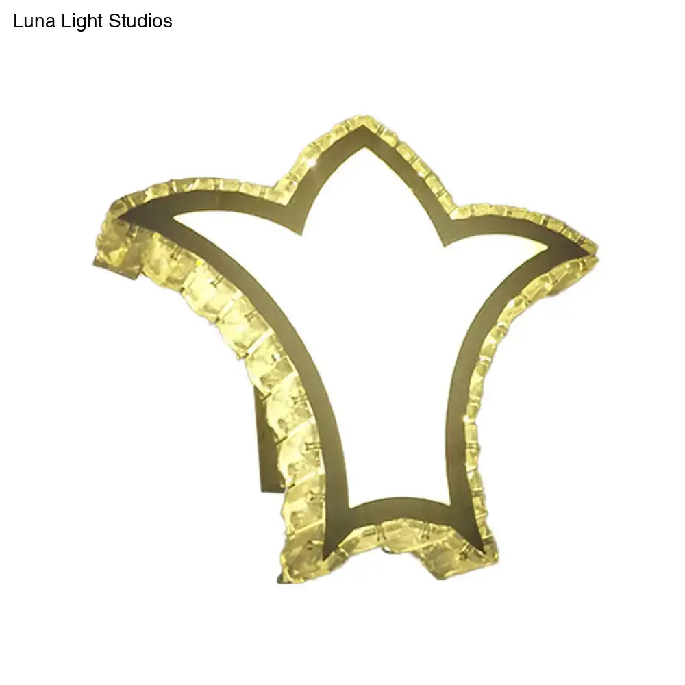 Modernist gold crown wall light with clear k9 crystal featuring a textured star shaped beaded edge and illuminated frame