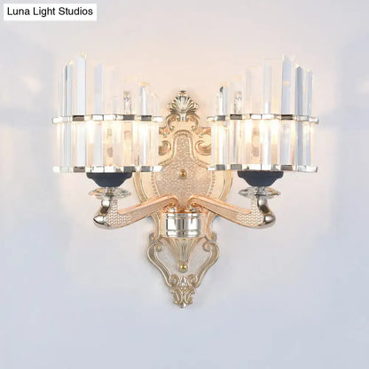 Gold-toned ornate wall light with conical crystal shades and decorative metal arms for living room use