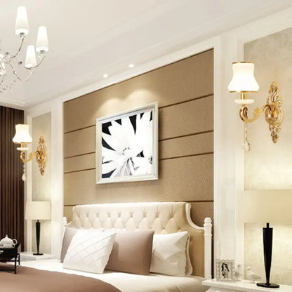 Cream-colored tufted bedhead with white frame alongside modernist gold wall sconce with glass shade direct wired electric