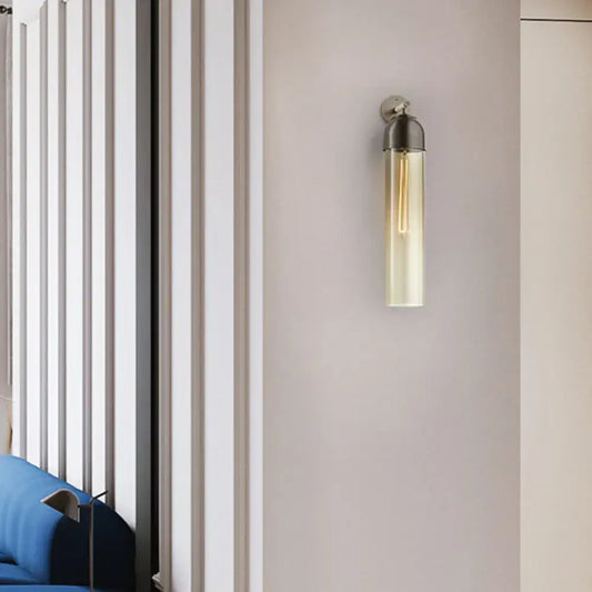 Modernist metallic tube sconce light with brushed finish and clear glass housing for bedroom use with curved arm
