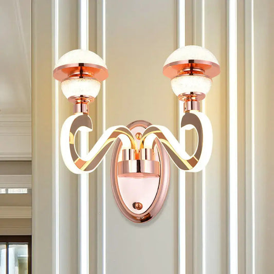 Modernist urn shape rose gold wall sconce with two glowing LED arms and frosted glass globe shades for bedroom lighting