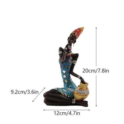 A decorative resin figurine of an african black woman in a blue patterned dress with a red and yellow headdress for decorbites black women decor