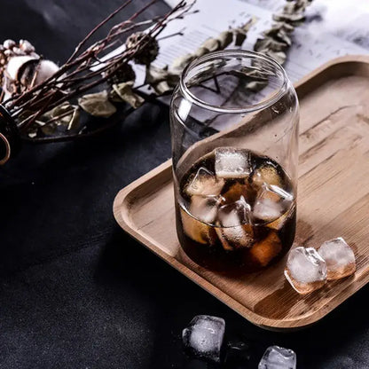 Clear glass motivational engraved shape beer glass cup filled with dark iced beverage on wooden tray