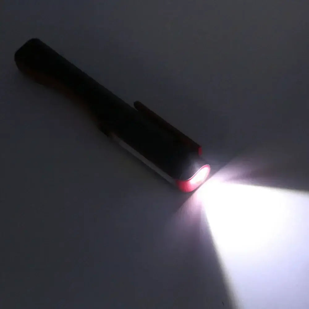 Black decorbites cob led flashlight with red accent ring emitting bright white light for garage work use