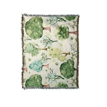 Rectangular multicolor jacquard tapestry blanket with stylized green brown trees on off white background and frayed edges