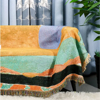 A cozy multicolor patchwork jacquard tapestry blanket with orange teal purple black stripes and fringed edges for living room use