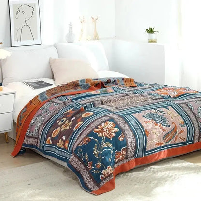 A multicolored cotton gauze boho throw blanket featuring a patterned patchwork in deep teal and burnt orange decorbites cotton gauze