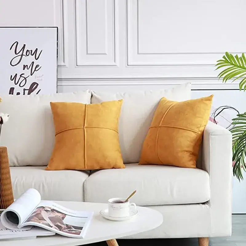 Two mustard yellow cross faux suede pillow covers with quilted cross stitch design on white sofa for living room decorbites decor