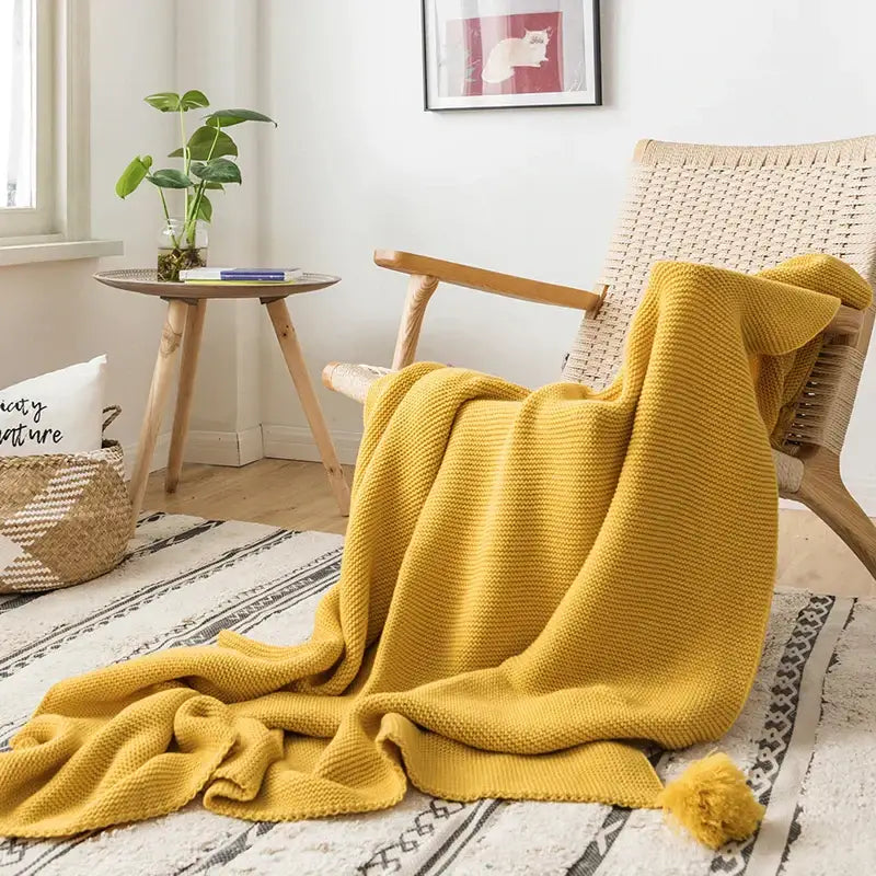 A cozy mustard yellow knit pompom tassel throw blanket with textured weave ideal for bedroom decorbites decor