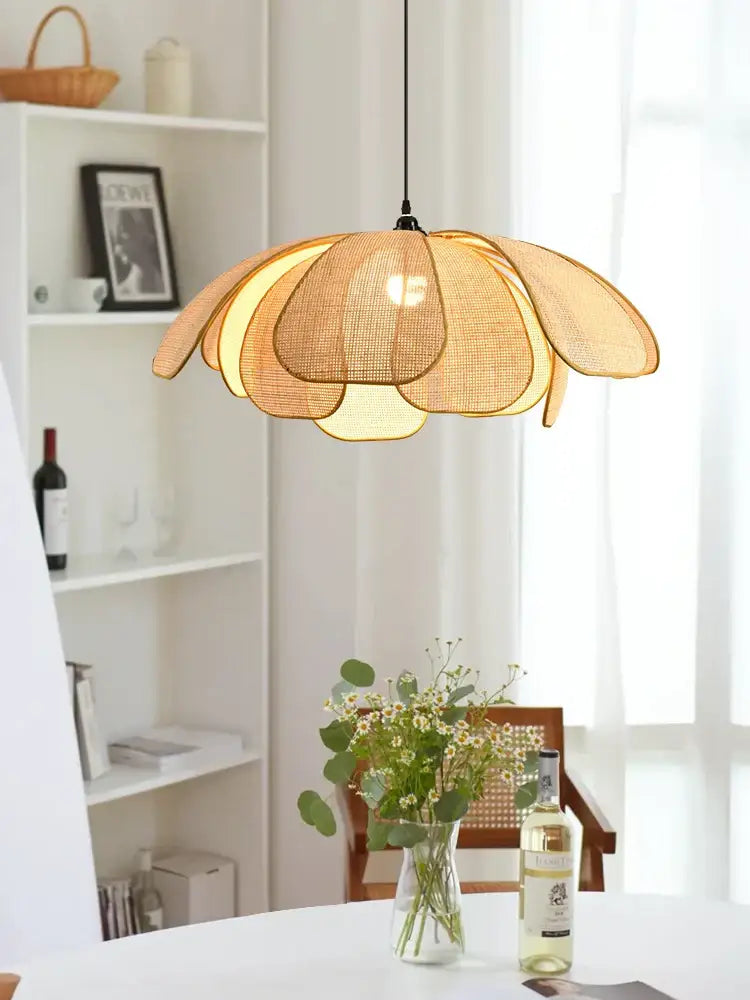 Natural rattan pendant light with warm-toned layered petal design hanging from a black cord as a dining room light source