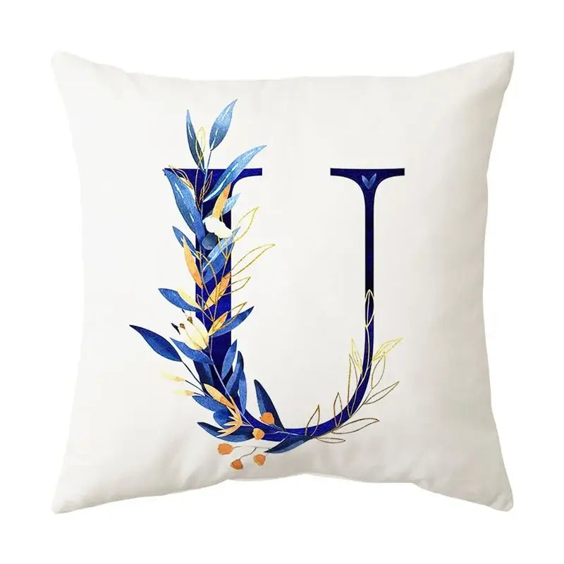 White throw pillow featuring a decorative letter u with blue and gold foliage in decorbites blue alphabet style