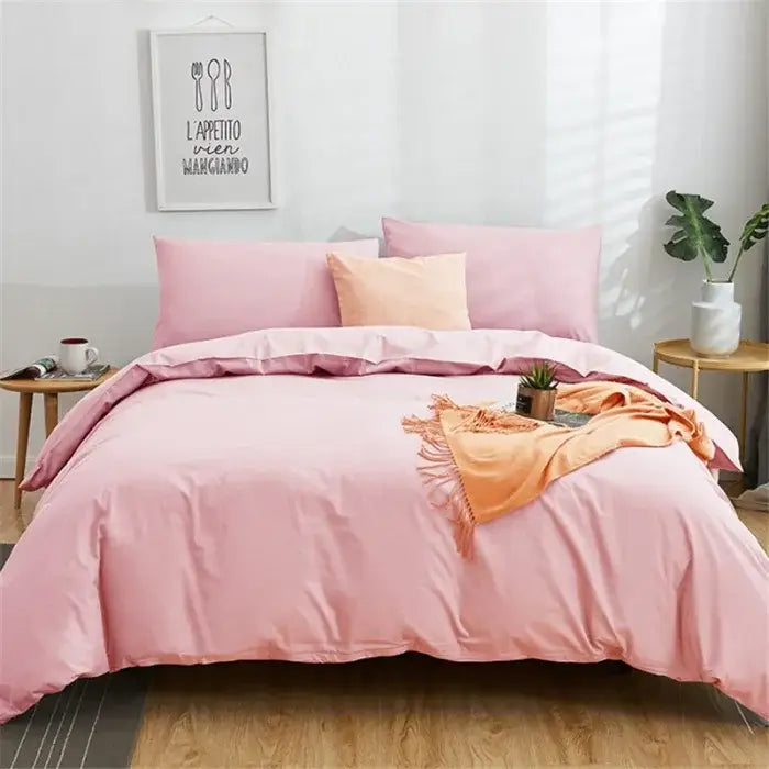 Pink satin-like duvet cover set with matching pillowcases and peach accent pillow on a solid color decorbites cotton 4pcs bedding set