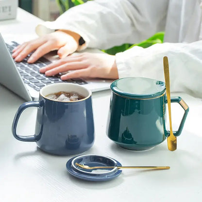 Deep teal ceramic mug set with gold-trimmed lid handle and matching spoon from navy and emerald ceramic mug set