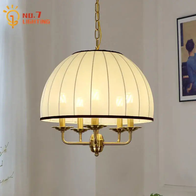 Gold-toned brass pendant light with cream neoclassical vertically ribbed fabric shade and five candle-style arms by decorbites