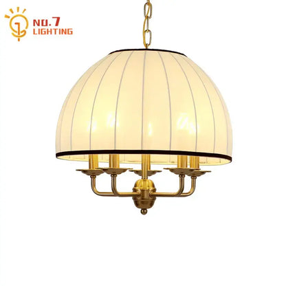 A warm-toned cream neoclassical pendant light with a brass frame and vertical ribbed fabric shade for dining room decorbites