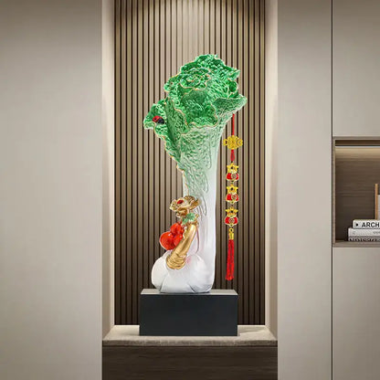 A glossy green and white ceramic decorbites cabbage ornament with golden accents and red tassels for office decor