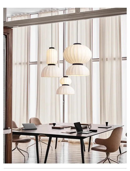 White pleated paper lantern light with black metal accents hanging in a dining room shop hanging light fixture